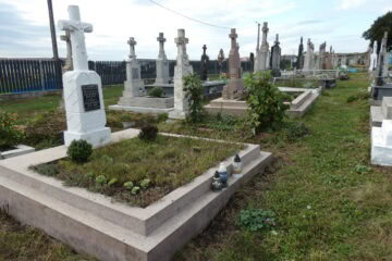 Могилы на цвинтарі в Буцачі, старі хрести та пам'ятники, покриті рослинами і квітами.