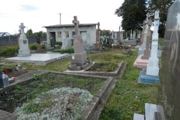 Могили на цвинтарі Буцак в Україні з пам’ятними надгробками та квітковими виробами.