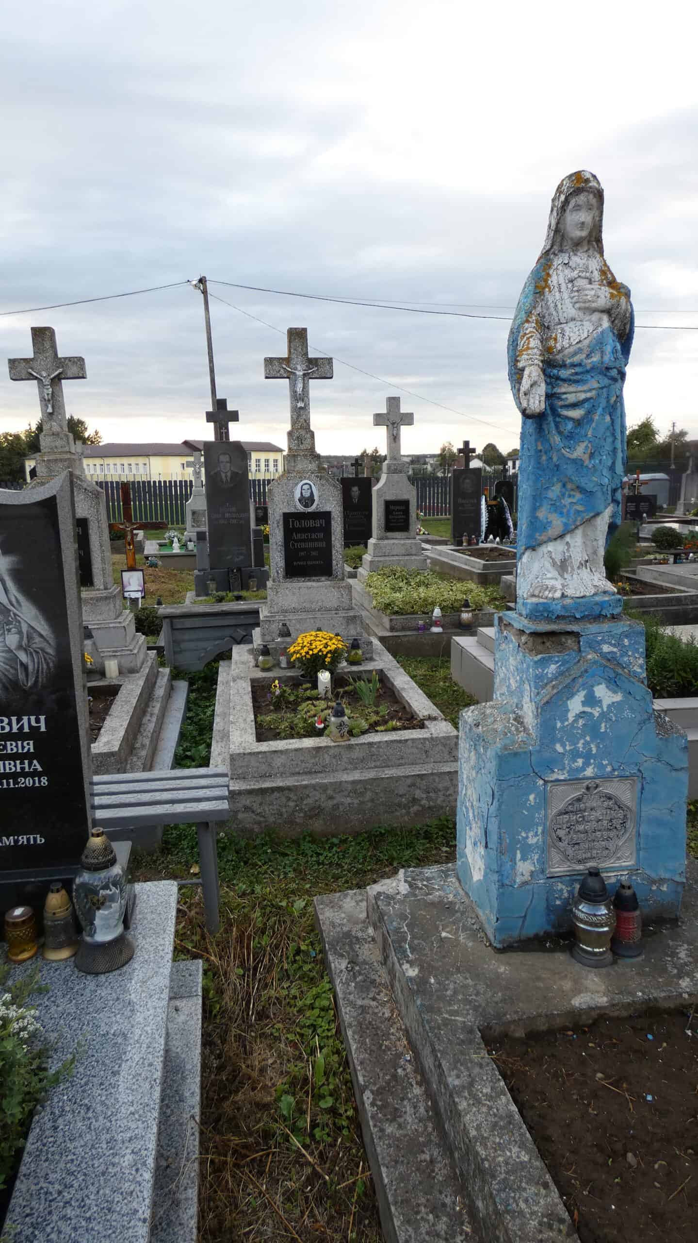 Могильний пам'ятник з іконою Богородиці на українському цвинтарі, старий та пошкоджений, символ пам'яті та скорботи.