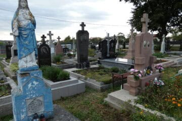 Вигляд цвинтаря в Бучачі з різноманітними пам’ятниками та квітами, спокійна атмосфера для поминання.