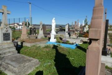 Могили на цвинтарі Буцачці з квітами та пам’ятними таблицями, фото на сонці.