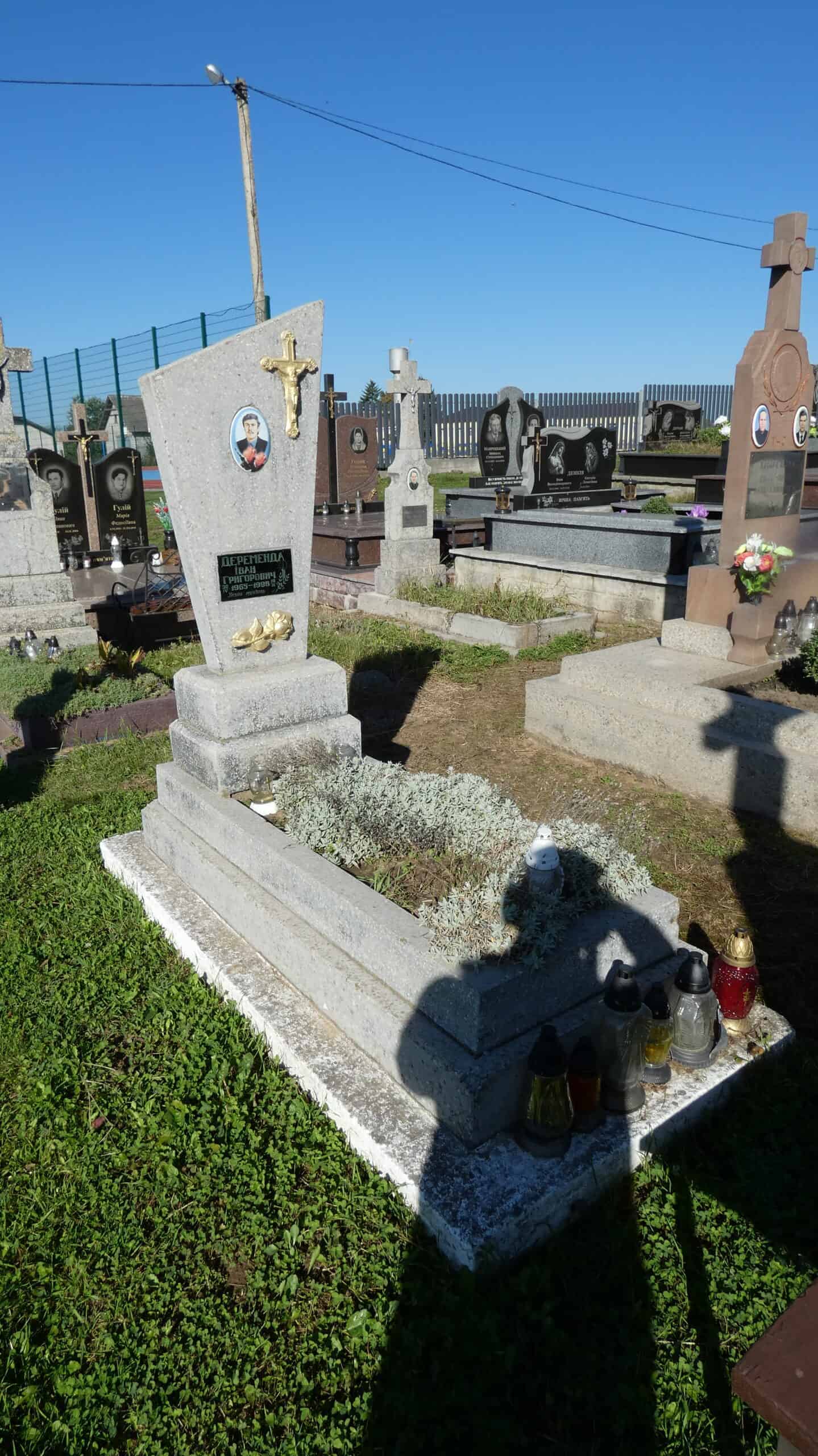 Могила на цвинтарі у Буцачі, кладовище, пам’ятник з хрестом у саду.