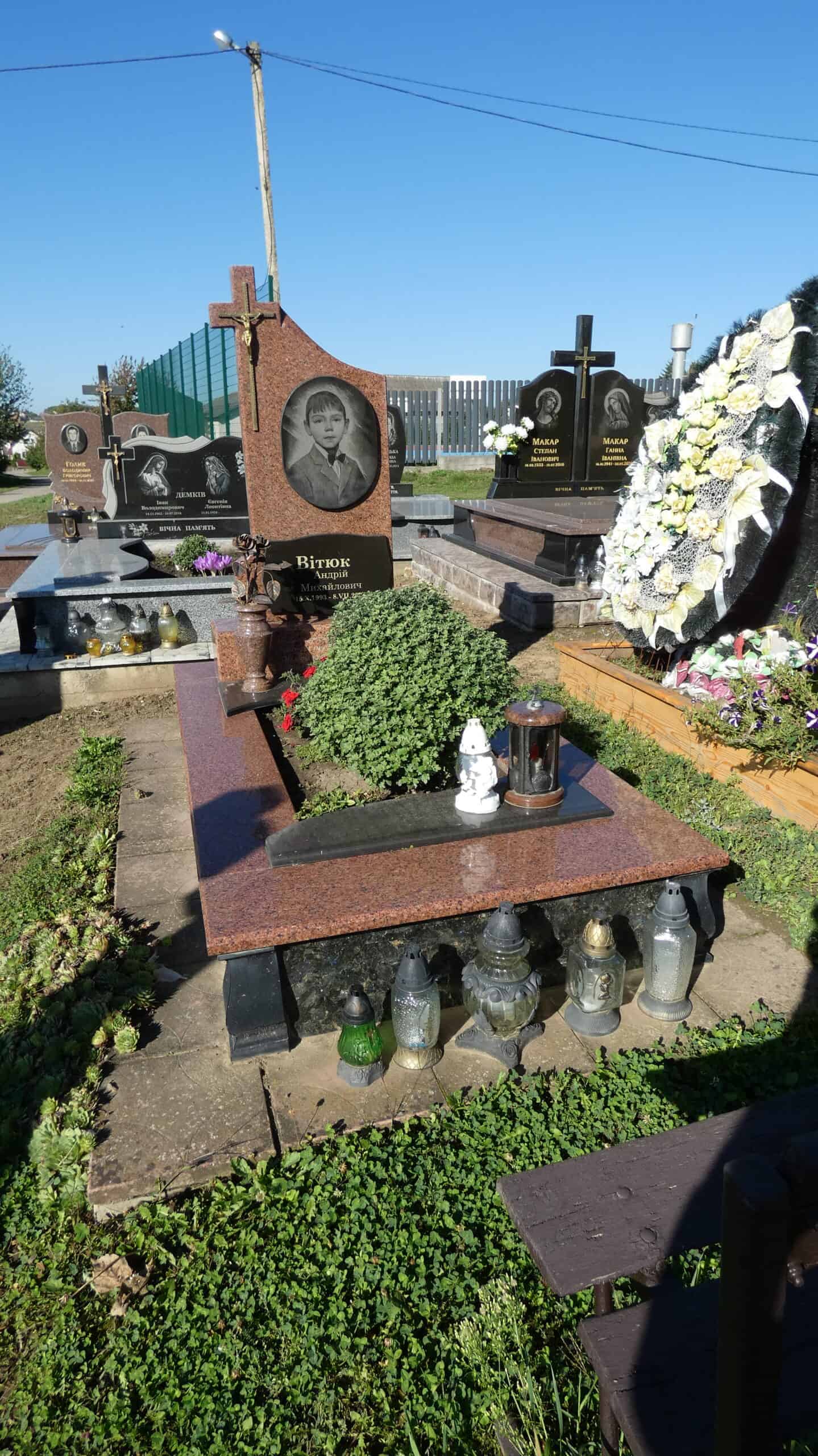 Вигляд могили з квітами та лампами на цвинтарі, пам'ять про близьких.