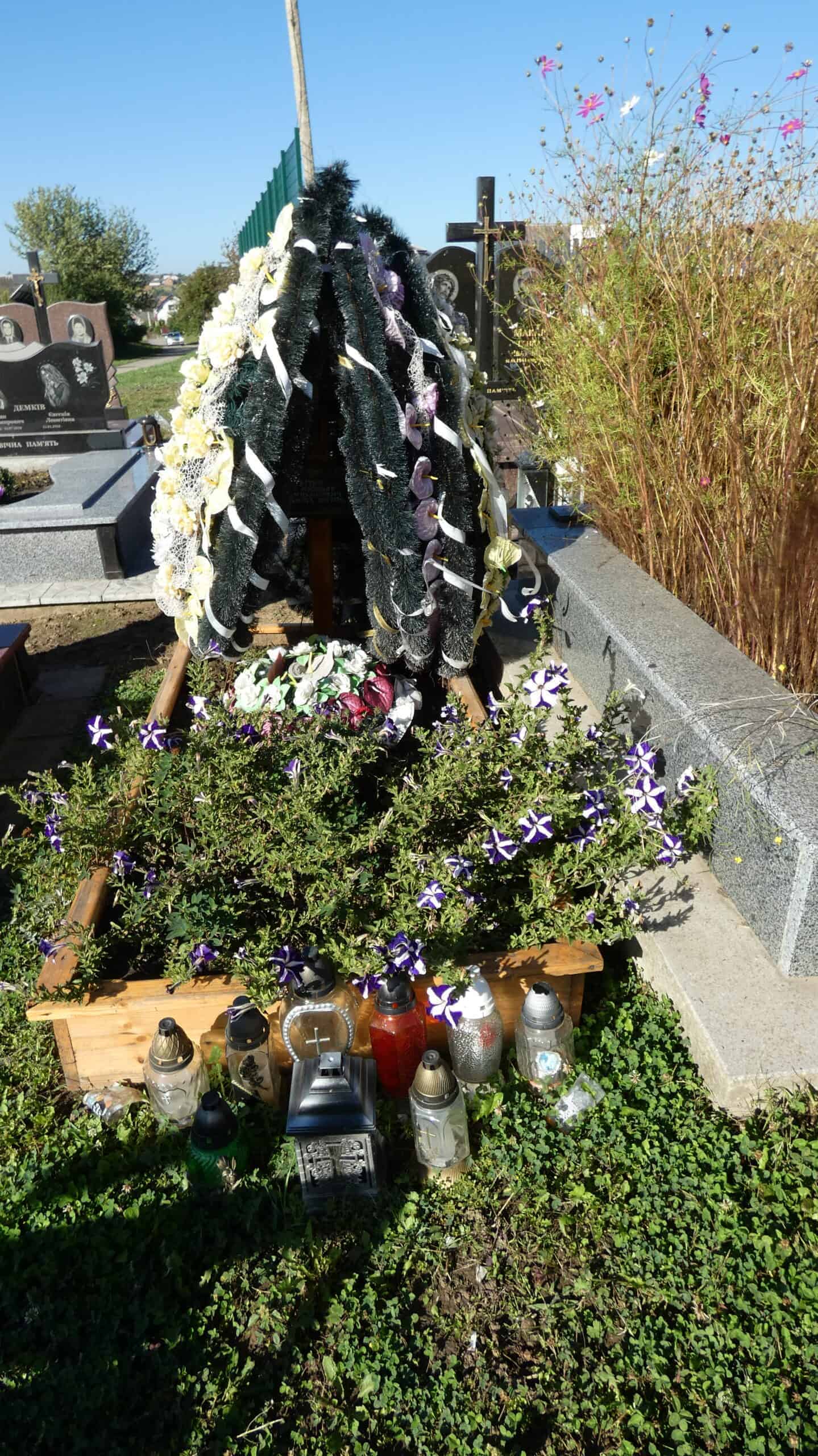 Могила на цвинтарі Буцачі, пам'ять про рідних з квітами та лампадками.