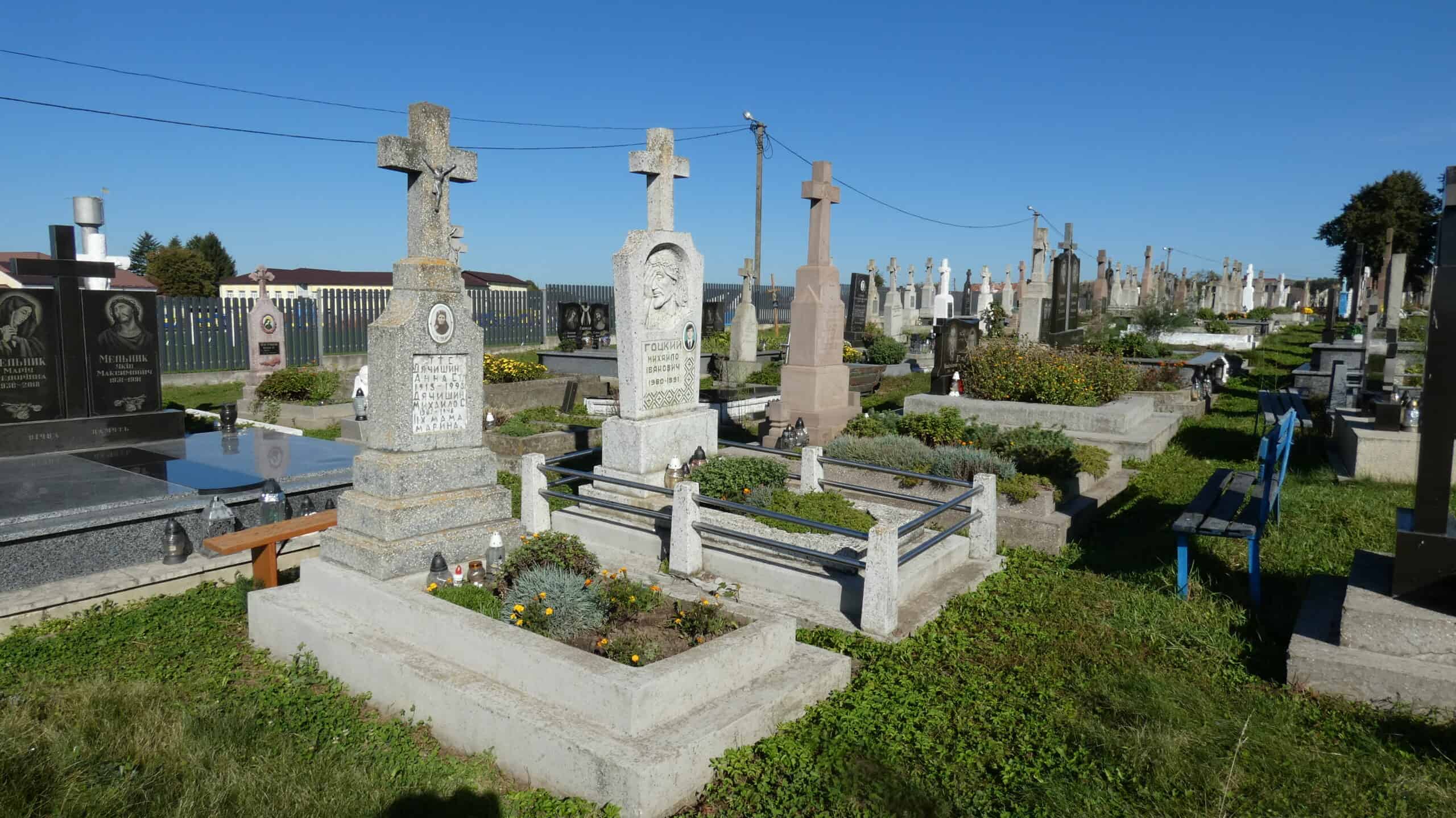 Вигляд цвинтаря в Буцачі з могилами та пам’ятниками під яскравим сонцем.