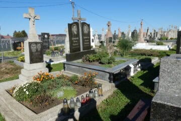 Могили на цвинтарі в Бучачі з квітами і лампадками.