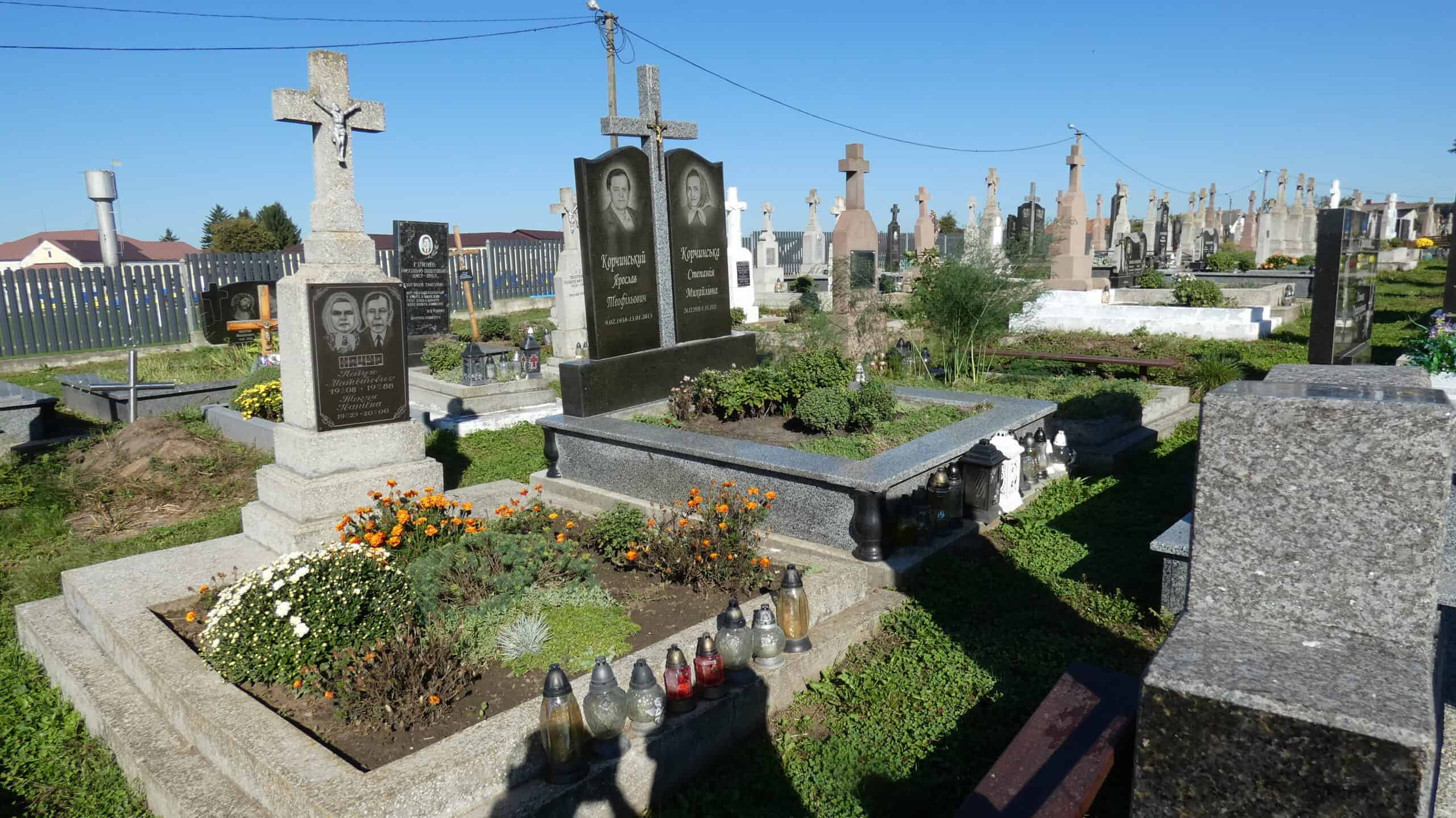 Могили на цвинтарі в Бучачі з квітами і лампадками.