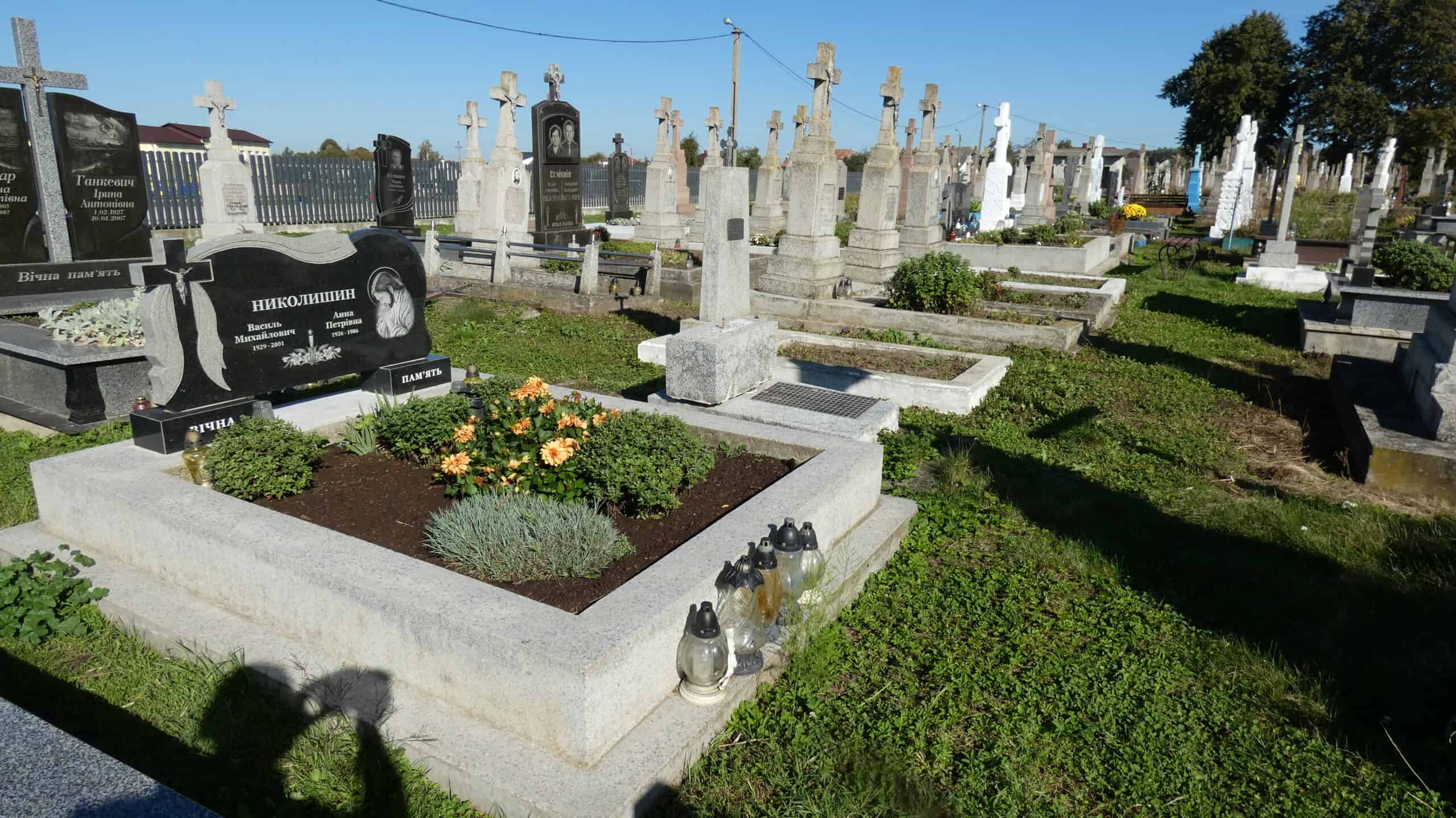 Могила з квітами та лампадами на цвинтарі Буцачі, України.