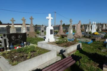 Могили з хрестами на українському цвинтарі, панорама пам'ятників і квітів.