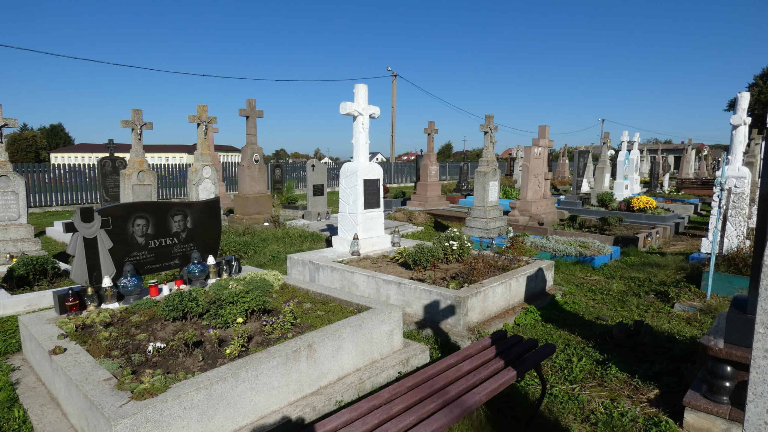 Могили з хрестами на українському цвинтарі, панорама пам'ятників і квітів.