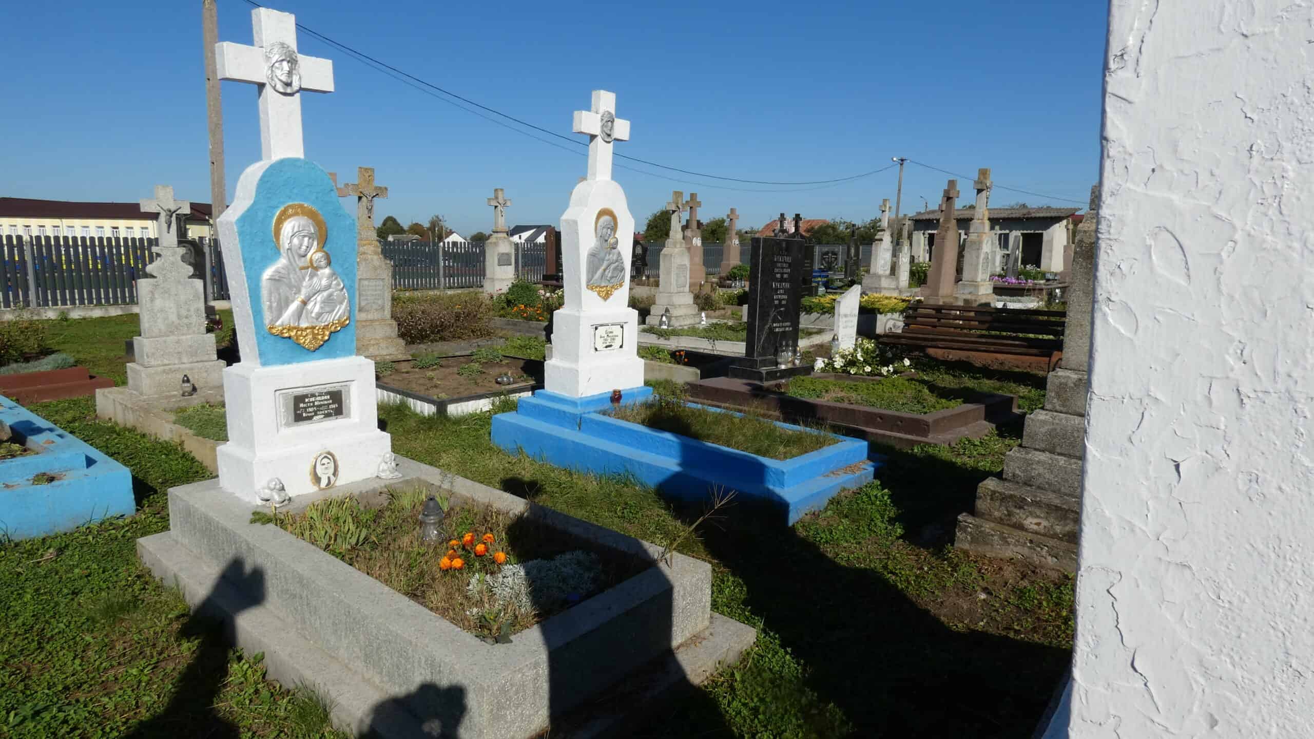 Могили на цвинтарі в Буцачі, покриті квітами та символічними пам’ятниками.