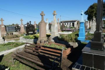 Могили на кладовищі в Буцкачу з хрестами та квітами, пам’ятники та лавки для відвідувачів.