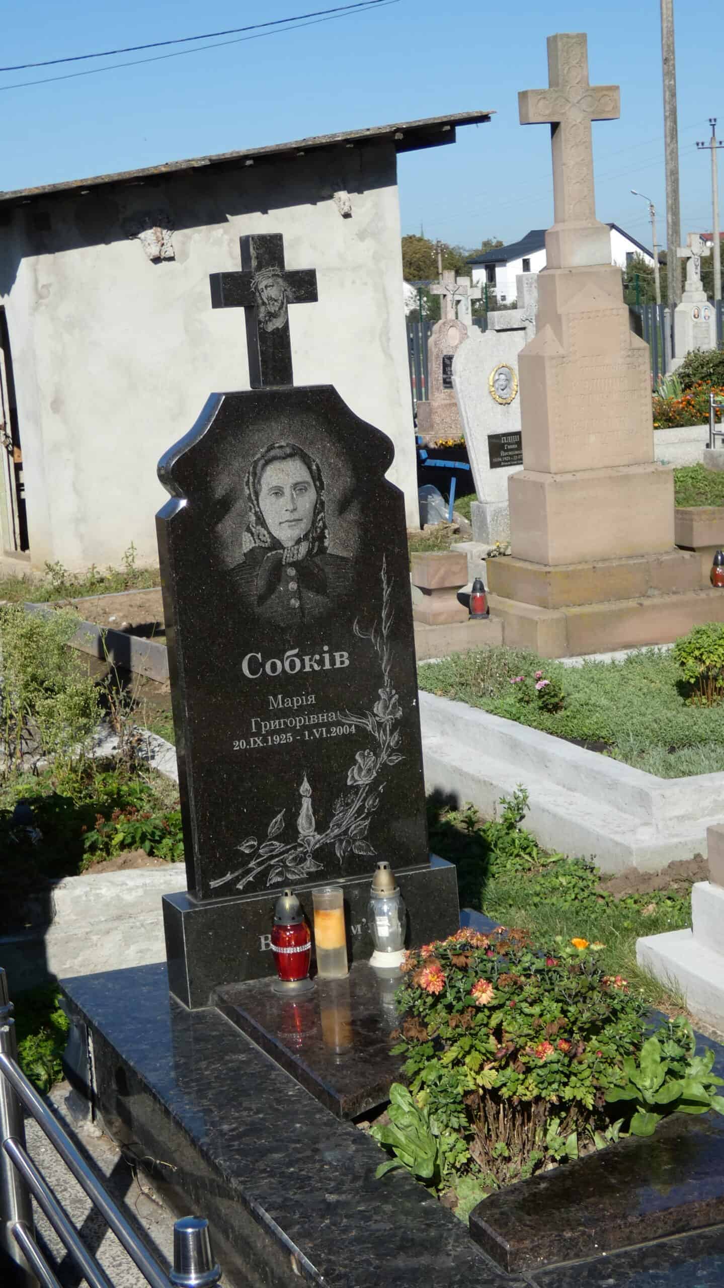 Меморіальний пам’ятник на цвинтарі в Буцачі зі скульптурою жінки та хрестом, символ пам'яті та шани.