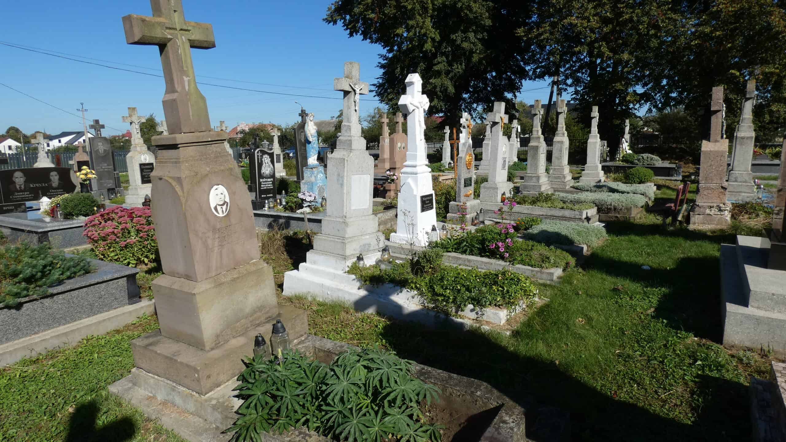 Могили в цвинтарі Буцач, історичне кладовище з пам’ятниками та квітами.