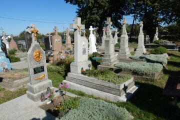 Біля могил на цвинтарі в Бучачі, історичні пам’ятники та кладовища з квітами і свічками.