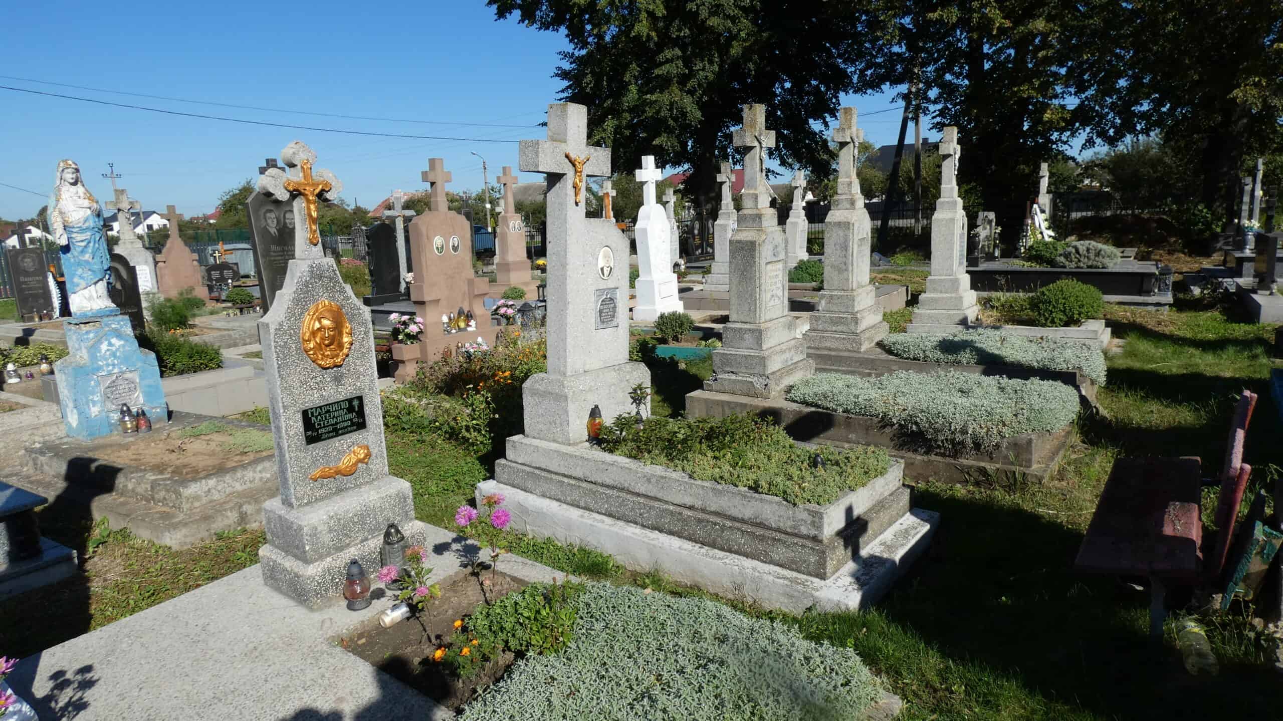 Біля могил на цвинтарі в Бучачі, історичні пам’ятники та кладовища з квітами і свічками.