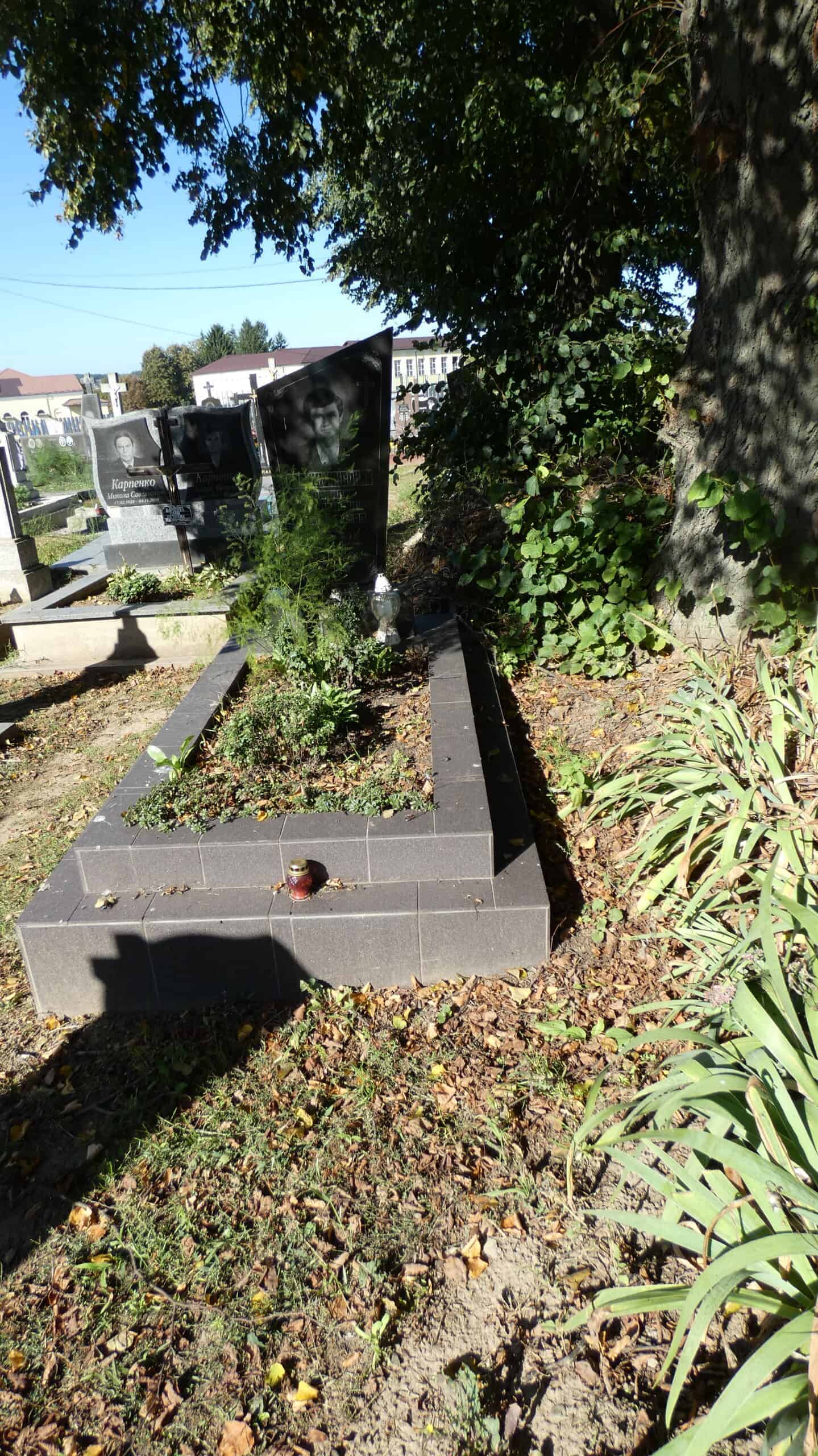 Могила на цвинтарі в Бучачі з квітами та пам’ятними плитами, спокій і пам'ять про рідних.