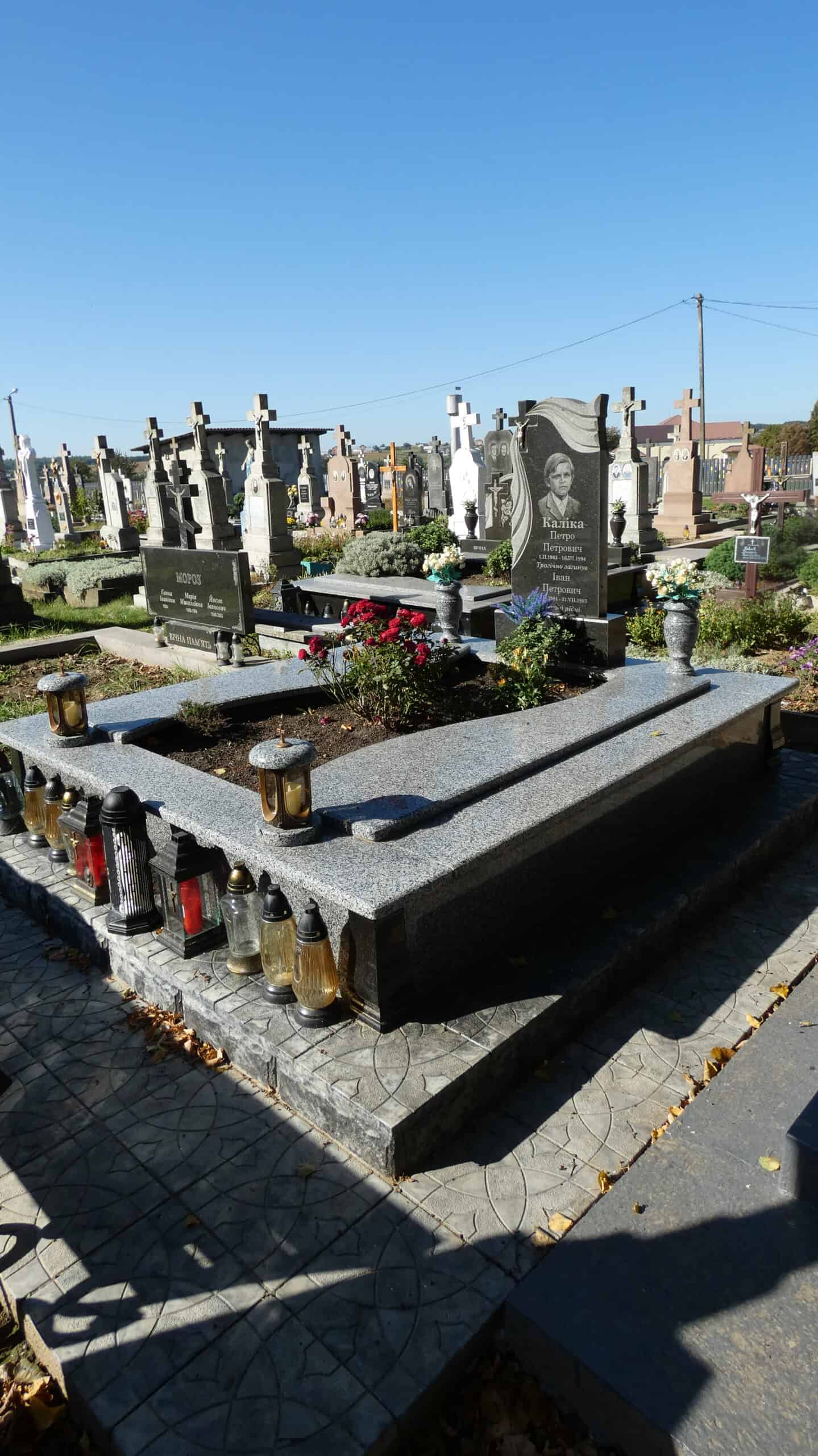 Могила з квітами та лампадами на цвинтарі в Буцачі, відпочиває душа.