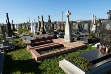 Могили на цвинтарі в Бучачі з пам'ятними плитами і хрестами, огляд у сонячну погоду.