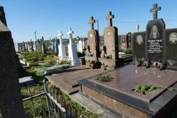 Меморіальні чорні гранітні надгробки з портретами та хрестами на цвинтарі Буцакіце.