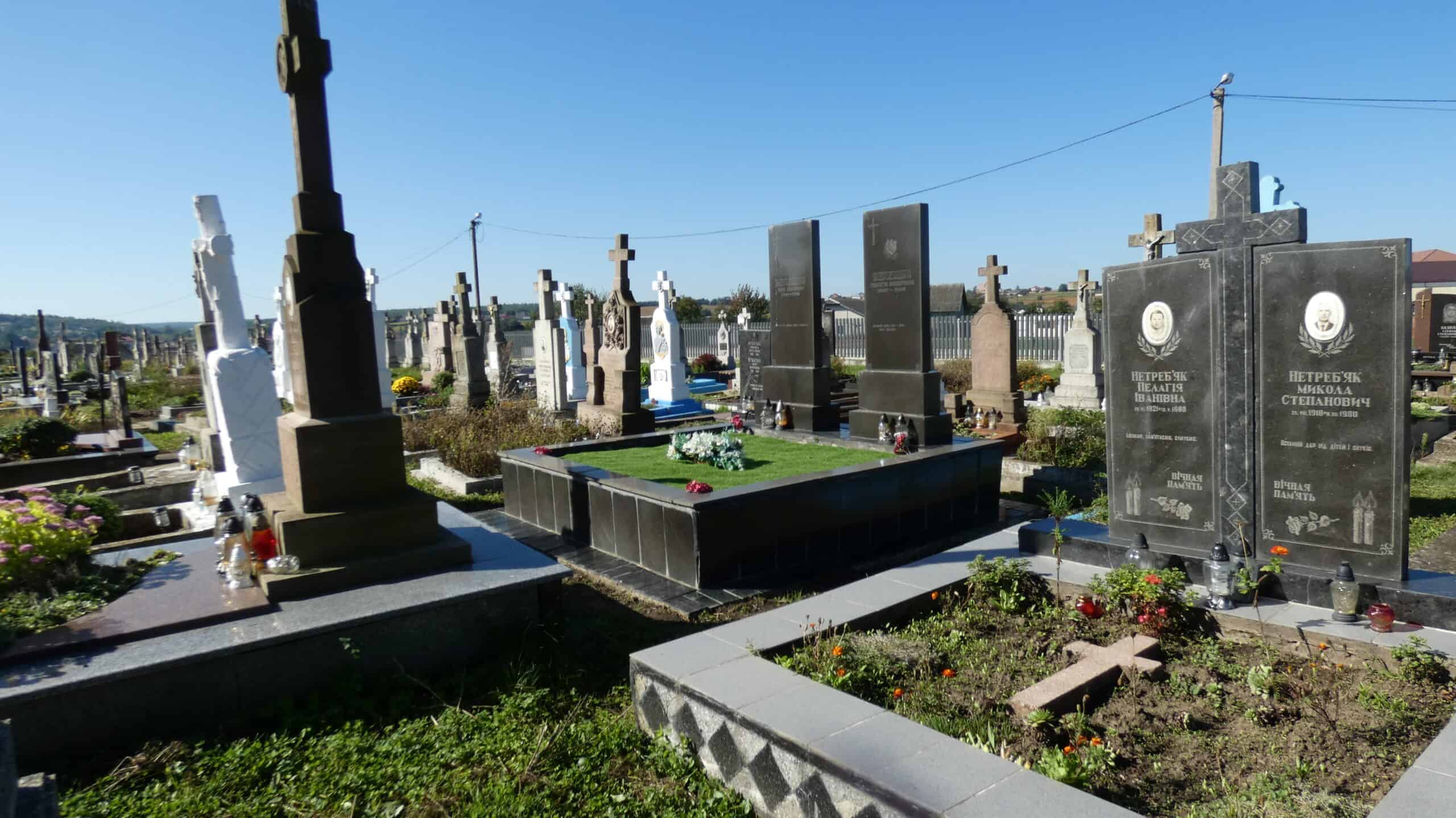 Вічний спокій на цвинтарі містечка Буцач, українські могили з пам'ятниками та квітами для рідних.