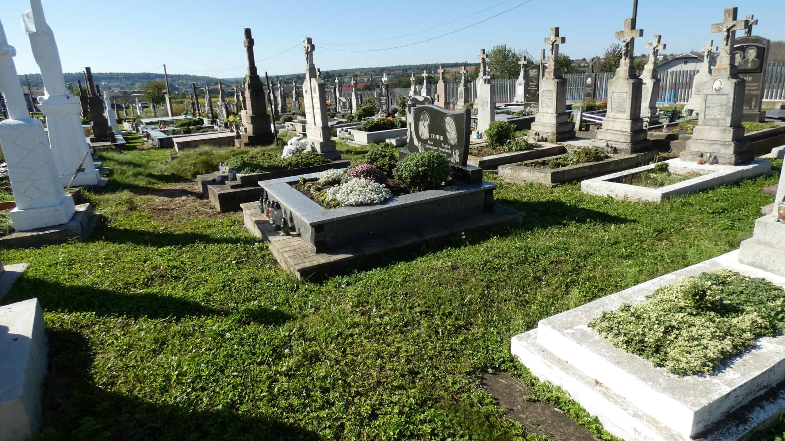 Вічний спочинок на цвинтарі Буцач, меморіальні надгробки та квіткові композиції.