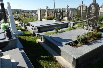 Відреставровані могили на цвинтарі в Буцачі, з декоративними надгробками та квітами.