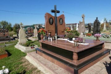 Меморіальний пам’ятник на цвинтарі з квітами й свічками, символ скорботи та пам’яті.