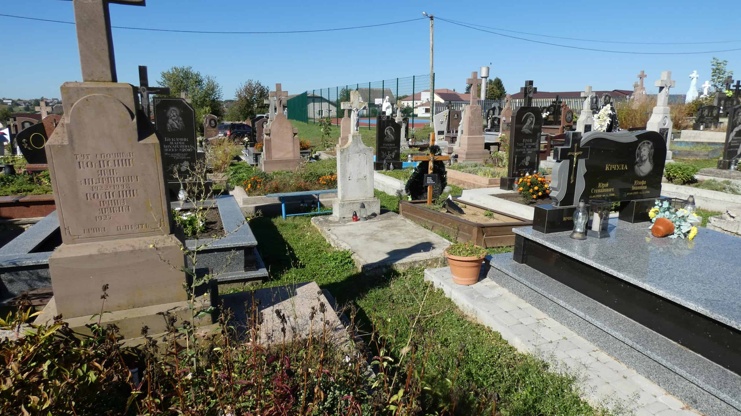 Могили на цвинтарі у Буцачі, поховання з пам’ятниками і квітами, історія та пам’ять у українському cemetery.