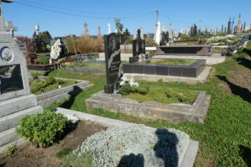 Вічний спочинок на цвинтарі Буцач, пам’ятники та могили з зеленими насадженнями.