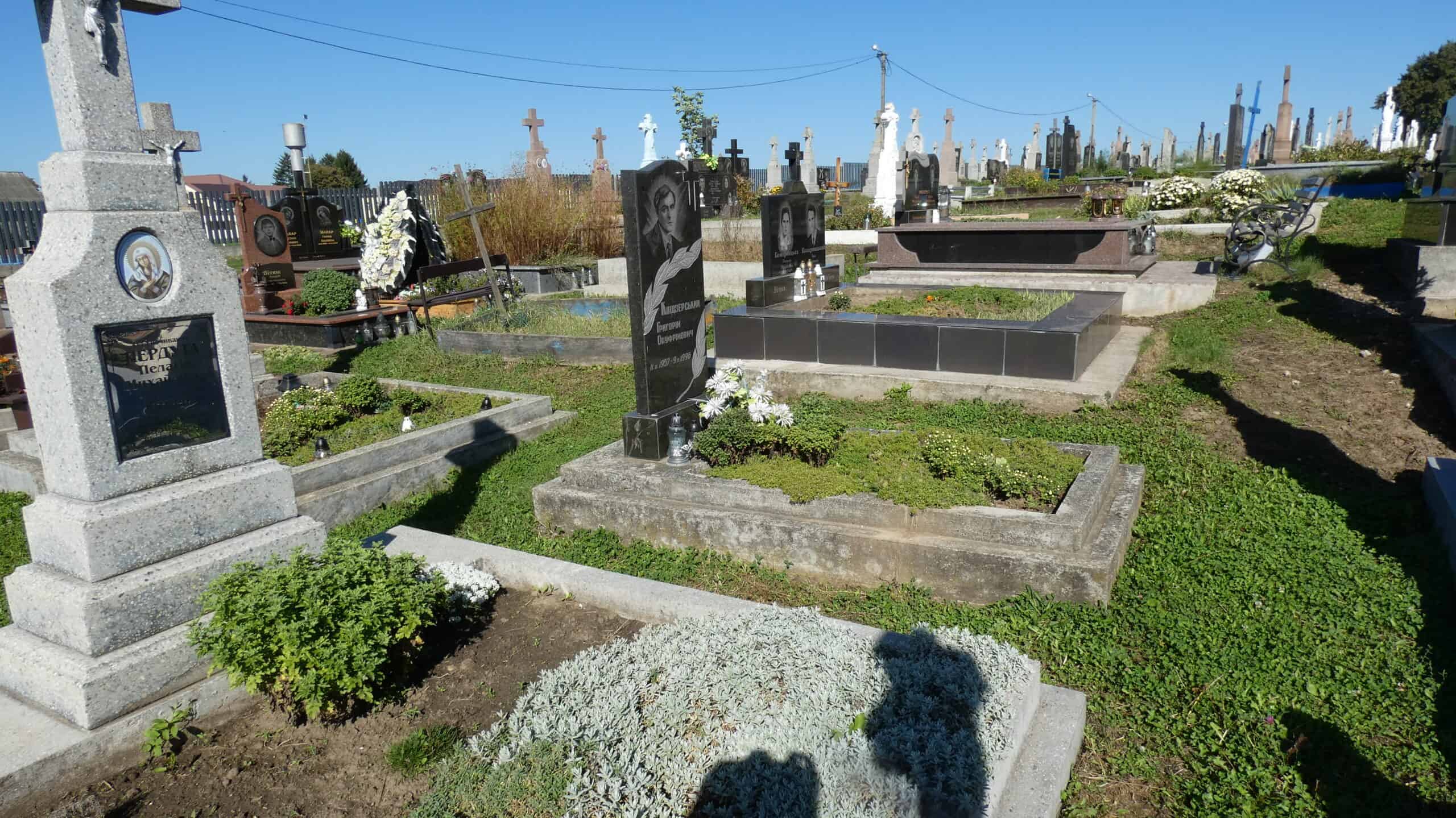 Вічний спочинок на цвинтарі Буцач, пам’ятники та могили з зеленими насадженнями.