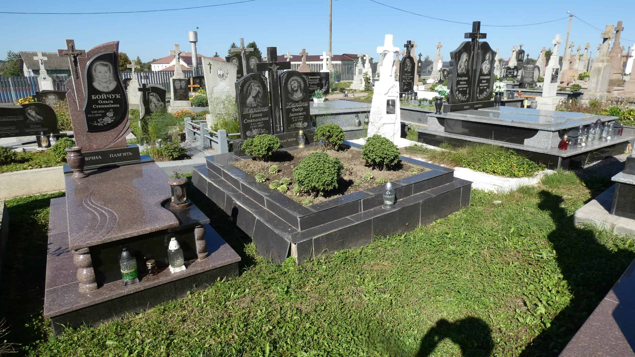 Вічний спокій на цвинтарі з красивим пам’ятником та зеленню, поховання в Буцачах, Україна.