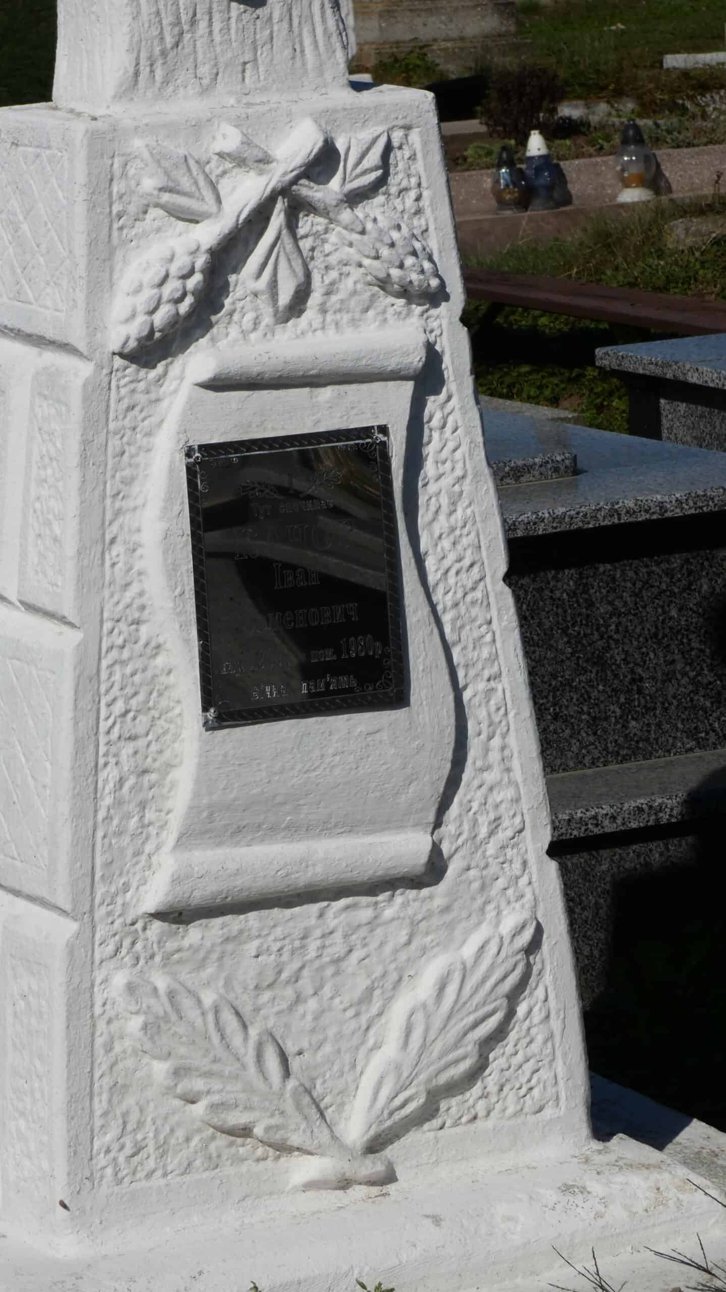 Могила на цвинтарі, декоративний пам’ятник із квітами та листям, пам’ять про померлого.