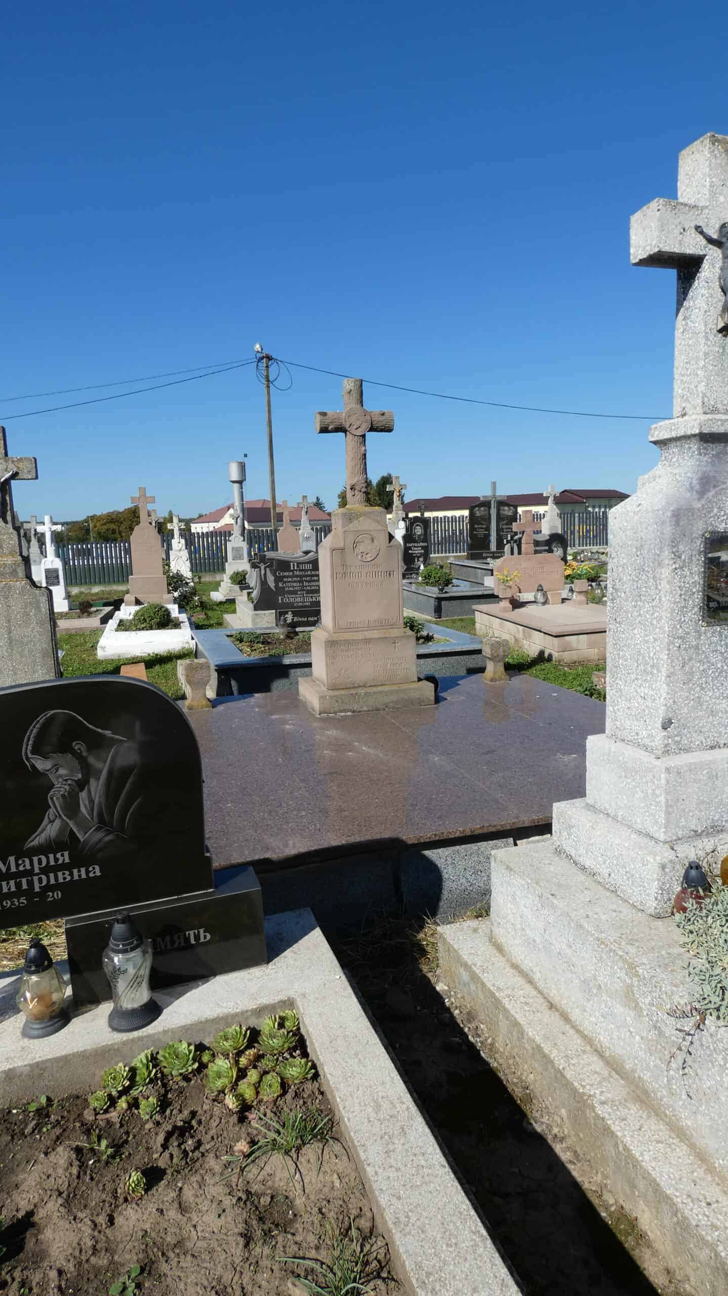 Могила з хрестом на цвинтарі Буцач, пам’ятник українським похованням, меморіальні надгробки.