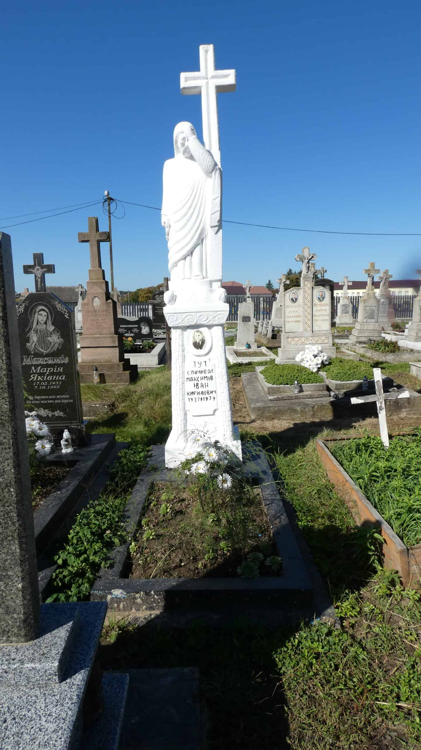 Вигляд пам'ятника на цвинтарі у Буцачі з хрестом і статуєю Ісуса Христа.