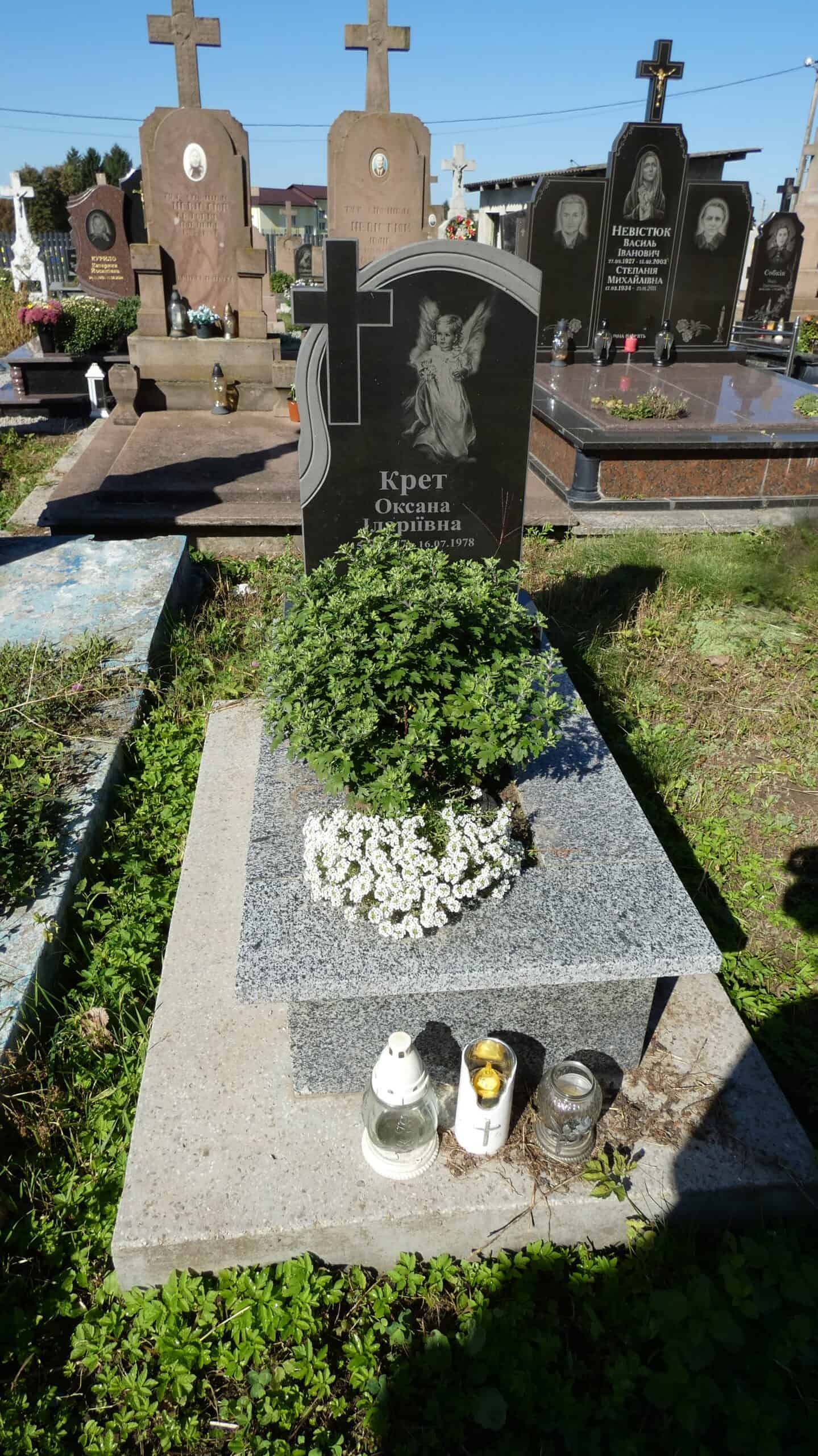 Могила з пам'ятником для Оксани Крет у цвинтарі Буцяч. Зелена рослина і квіти на могилі, символ пам’яті та шани.