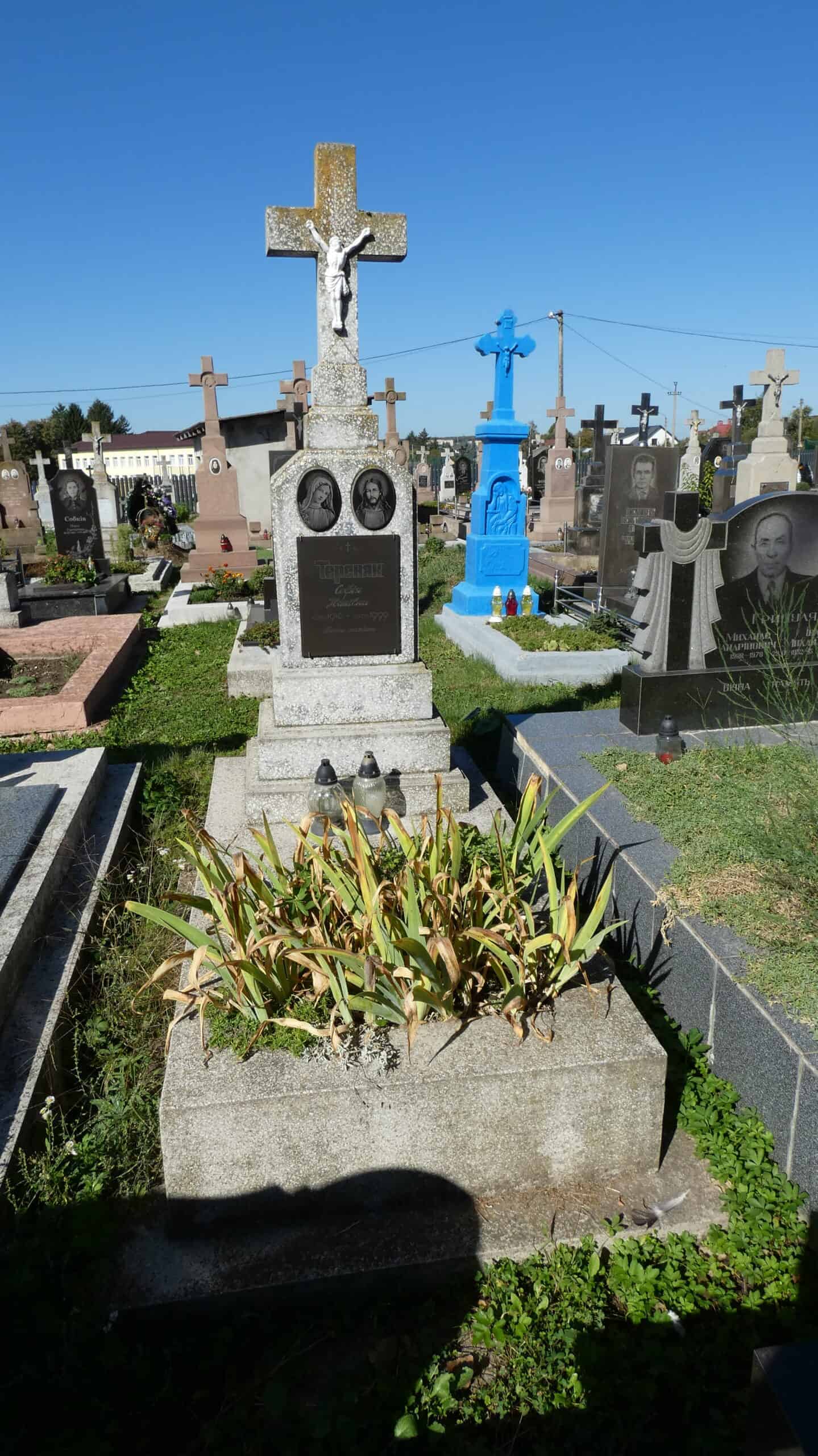 Могила на цвинтарі в Буцачі з хрестом та пам’ятними надгробками.