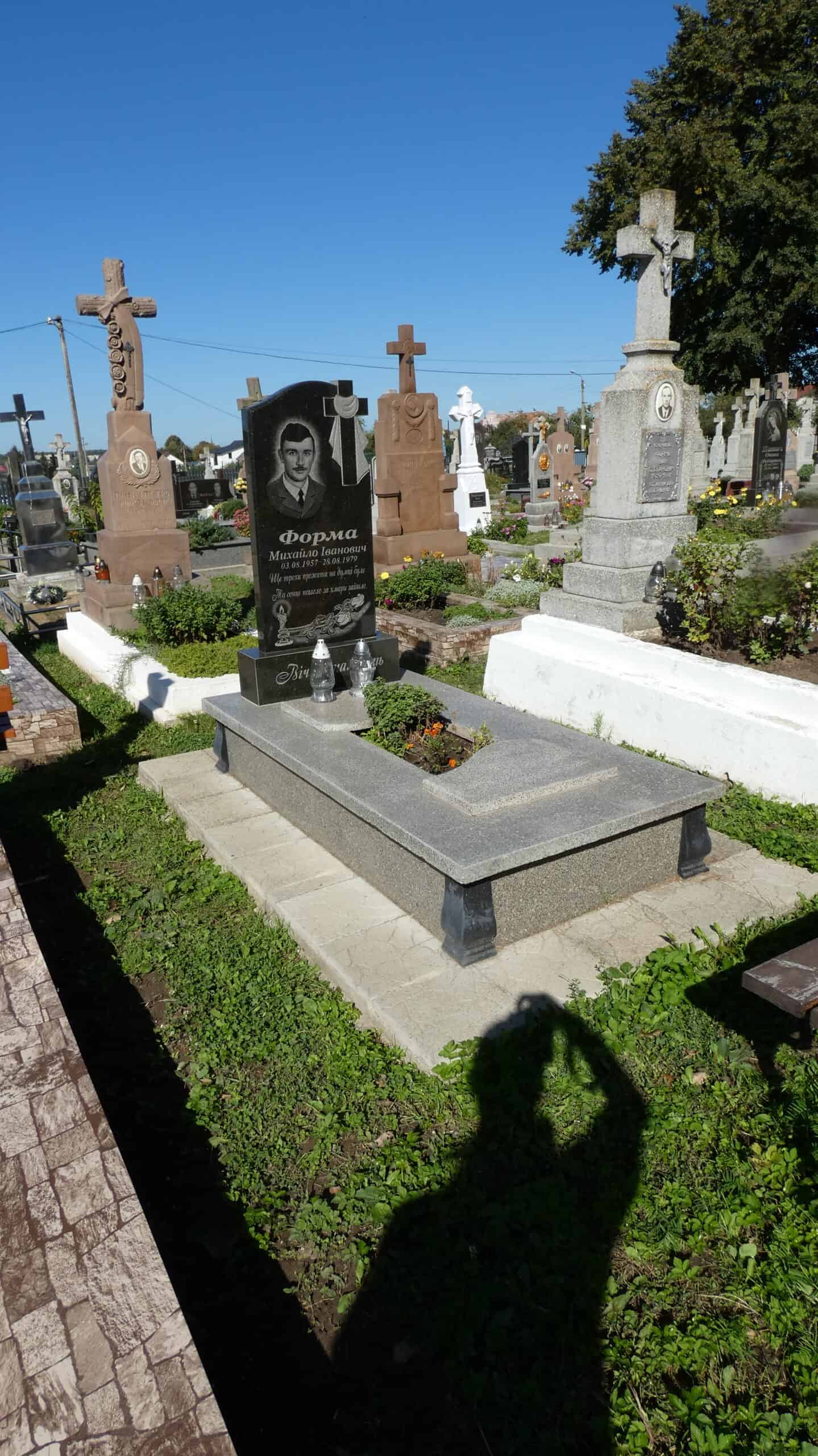 Могила на цвинтарі в Букачці з сучасним пам’ятником і квітами для покійного.