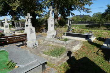 Меморіальні надгробки на старому цвинтарі Буцачі, могили з хрестами та квітами у яскравий сонячний день.