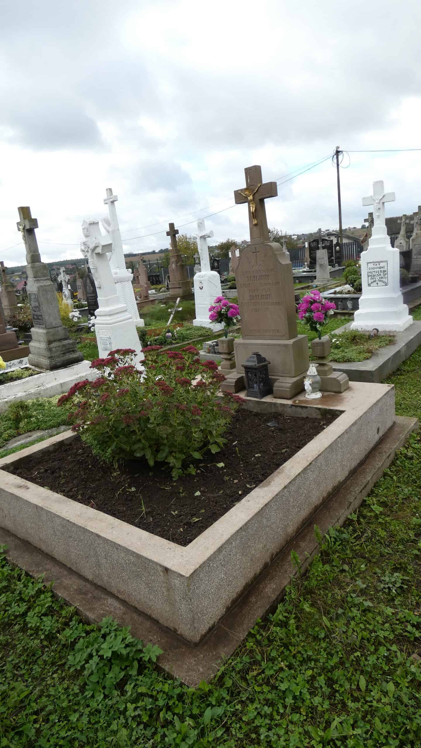 Могила з хрестом у цвинтарі Буцький, доглянута та з квітами, вічне місце спочинку.