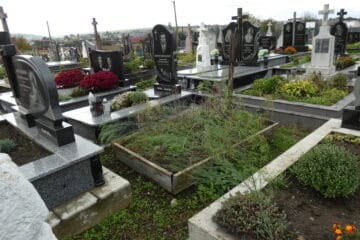 Могили на цвинтарі з сучасними пам’ятниками та квітами, похоронне місце в Україні.