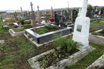 Висячий цвинтар у Буцачі, сучасне кладовище з кількома могилами та пам'ятниками, квітами і зеленню.