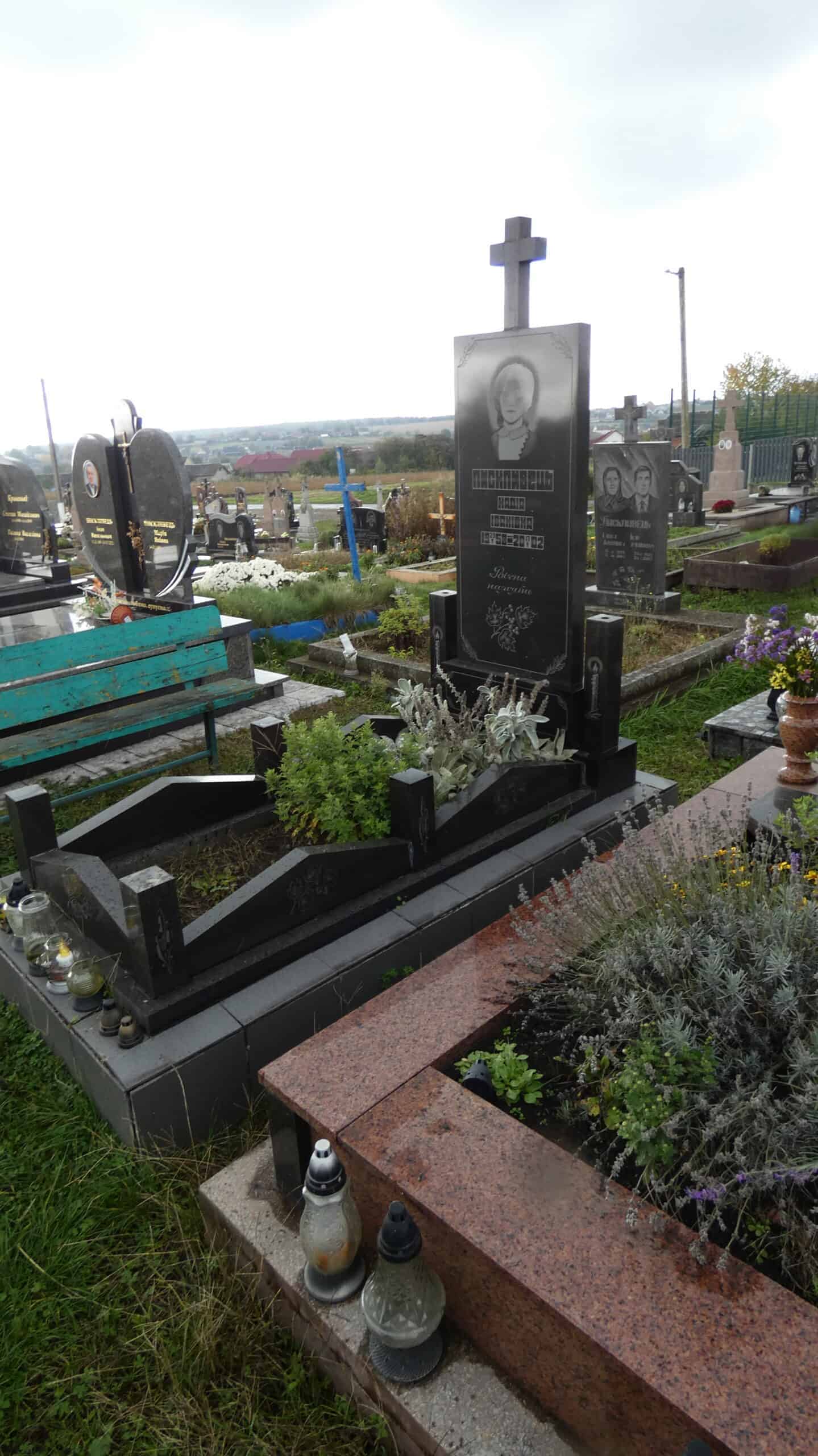 Могила з чорним гранітним пам'ятником на цвинтарі в Буцачі.