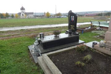 Могила на цвинтарі в Буцачі із чорним гранітним пам'ятником та квітами.