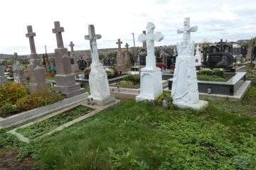 Могили на цвинтарі у Букачачі з хрестами та квітковими композиціями, меморіальні плити.