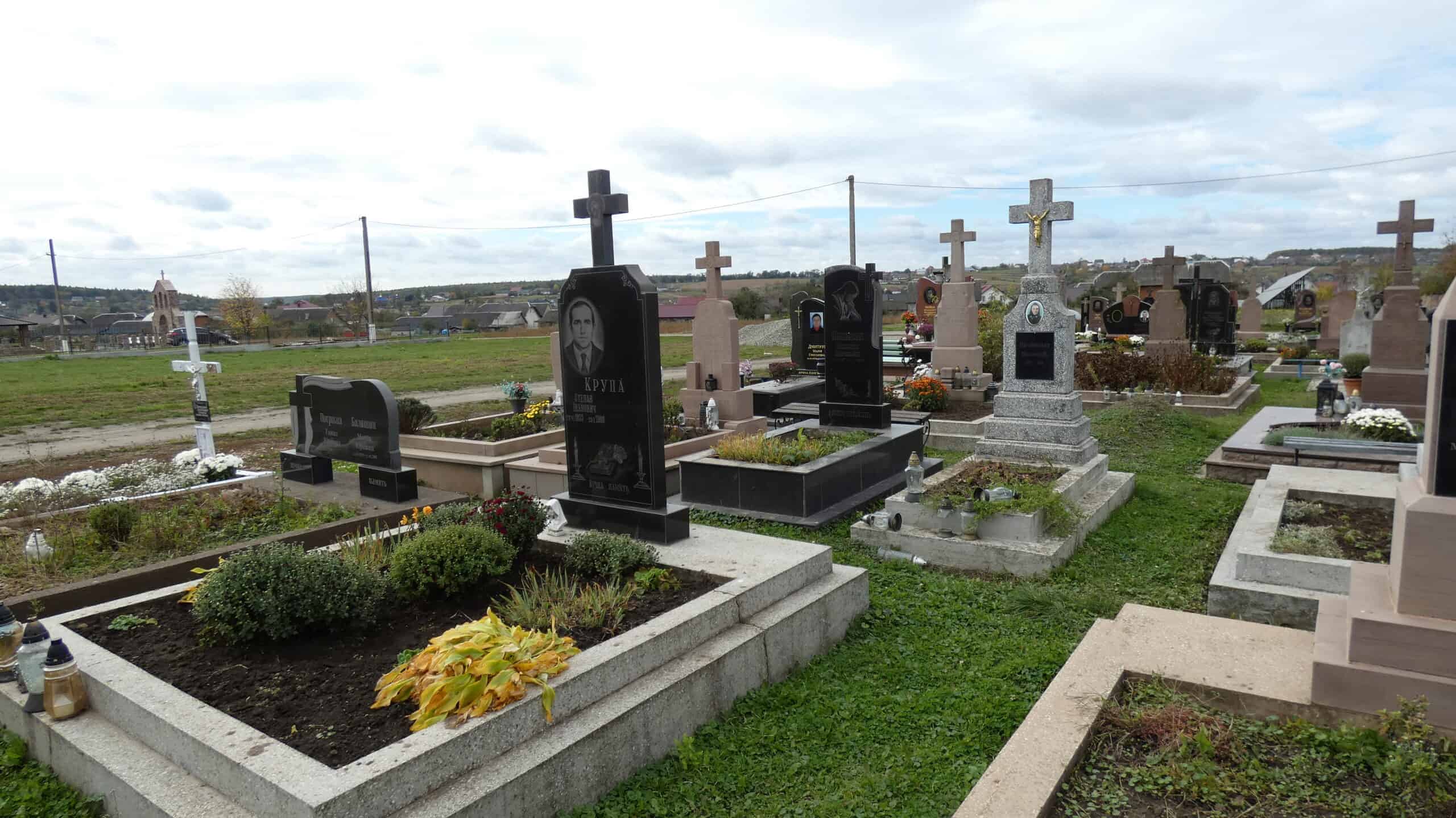 Могили на цвинтарі у Буцачі, сімейне кладовище, меморіальні пам'ятники та квіткові насадження.