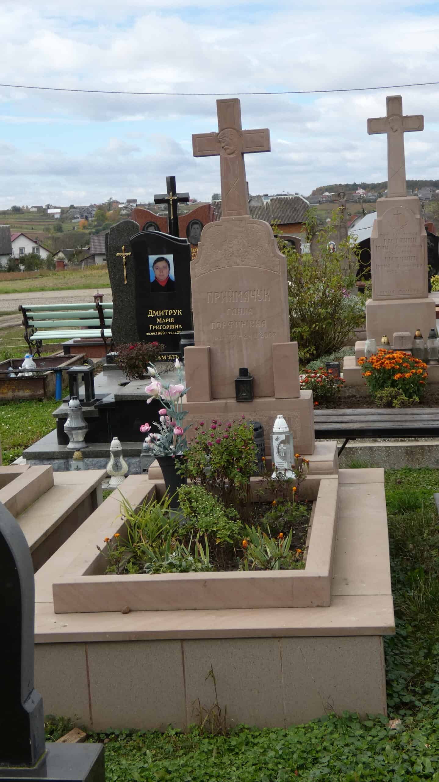 Могила з хрестом у цвинтарі Буцавець. Вічна пам’ять про рідних та близьких. Поблизу квіти та лампадки.