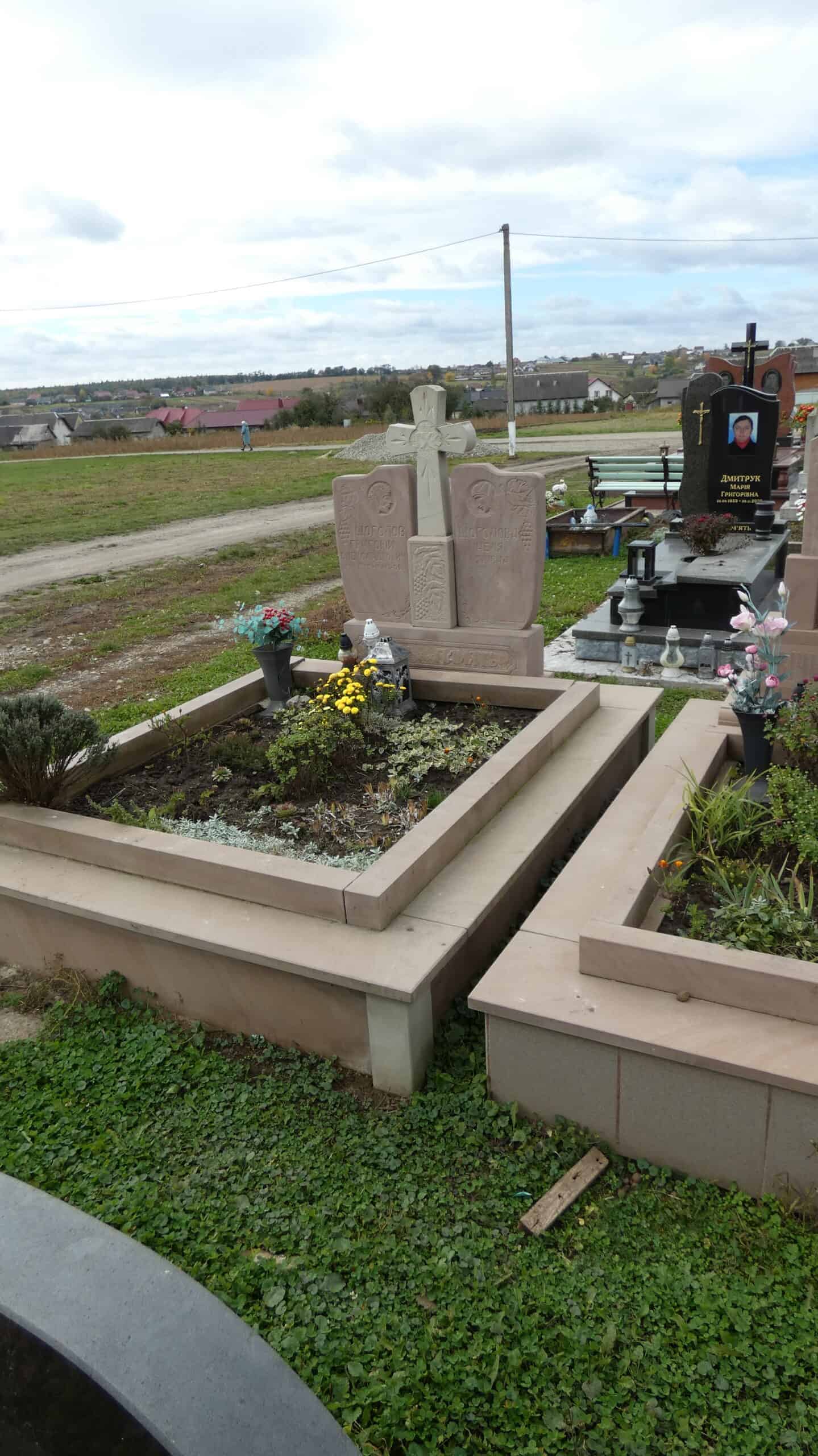 Могила на цвинтарі у Буцачі з квітами і пам’ятником у українському стилі.